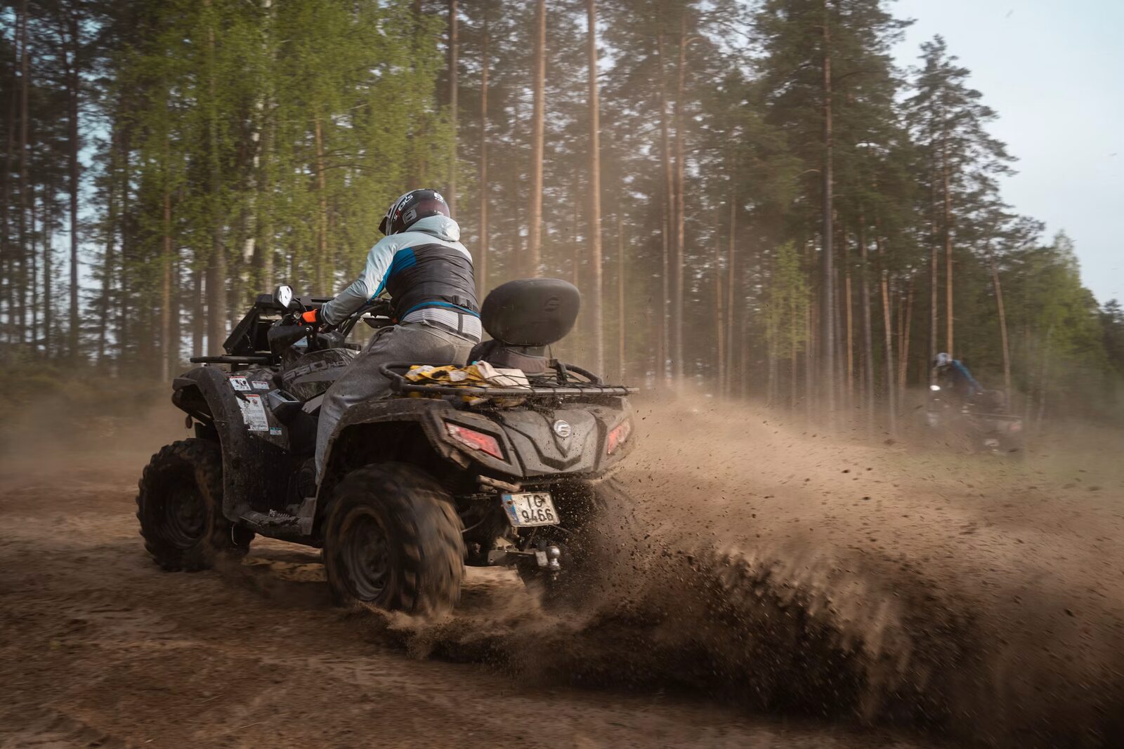 ATV kicking up dust on forest trail, muted palette